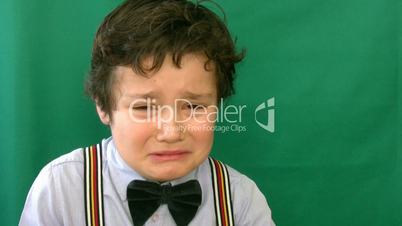 Boy crying  in front of a green screen