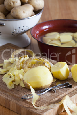 kartoffeln und kartoffelschäler auf schneidebrett