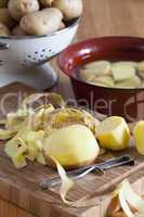 kartoffeln und kartoffelschäler auf schneidebrett