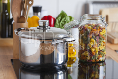 grosser kochtopf und glas mit bunten nudeln