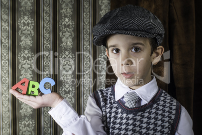 Child in vintage clothes hold letters a b c