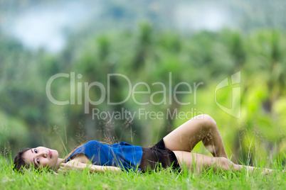 young filipina woman relaxing on green grass