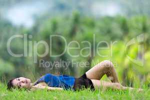 young filipina woman relaxing on green grass