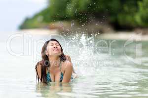 fun loving young woman splashing in the sea