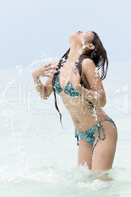 young woman in a bikini splashing in the sea