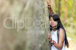 young thai girl holding onto a rock