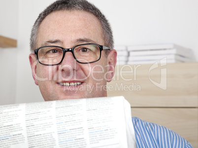 man with glasses reading newspaper