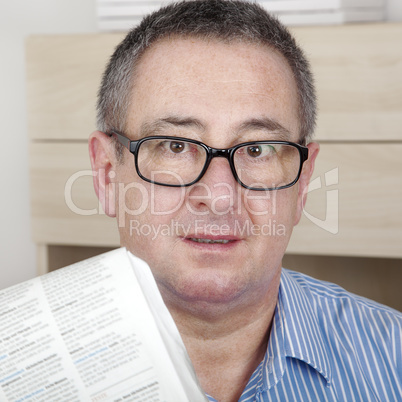 man with glasses reading newspaper