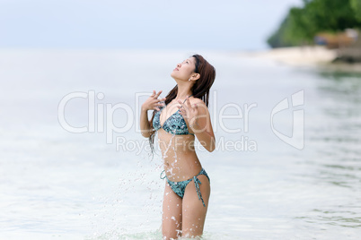 young woman in a bikini splashing in the sea