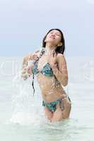 young woman in a bikini splashing in the sea