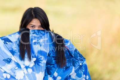 playful young girl peeking over her umbrella
