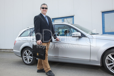 businessman standing on the car