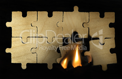 Burning wooden puzzle on dark background.