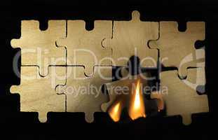 Burning wooden puzzle on dark background.