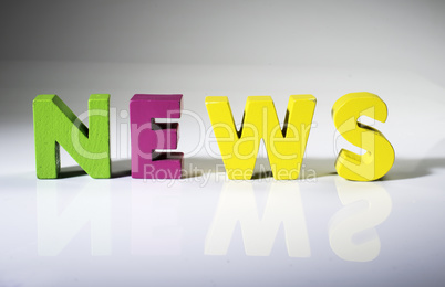 Multicolored word news made of wood.
