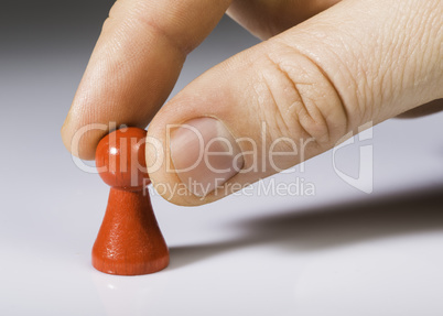 Hand holding red pawn on white background