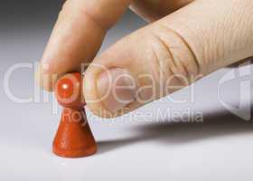 Hand holding red pawn on white background