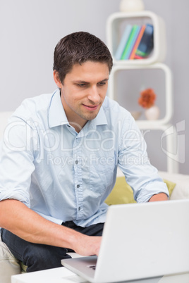 Smiling man using laptop at home