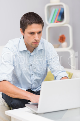 Serious man using laptop at home