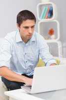 Serious man using laptop at home