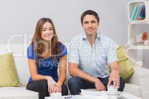 Portrait of a smiling young couple with bills at home