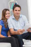 Smiling couple with bills in living room at home
