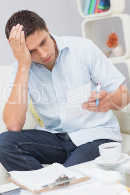 Worried young man paying his bills at home