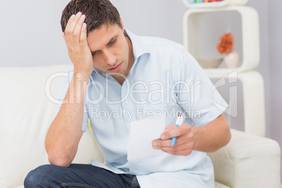 Worried young man paying his bills at home