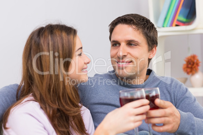 Smiling couple toasting wine glasses at home