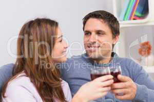 Smiling couple toasting wine glasses at home