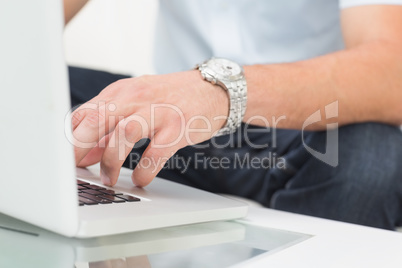 Mid section of a man using laptop on coffee table