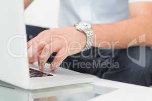Mid section of a man using laptop on coffee table