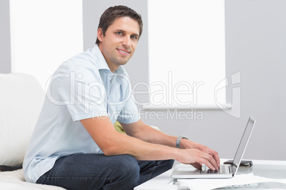 Portrait of smiling man using laptop in living room