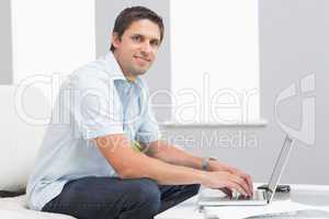 Portrait of smiling man using laptop in living room