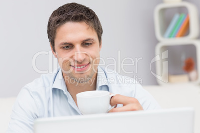 Close-up of a man with teacup using laptop at home