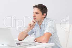 Side view of a serious man using laptop at home