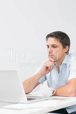 Serious young man using laptop at home