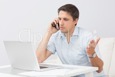 Man using laptop and cellphone in the living room