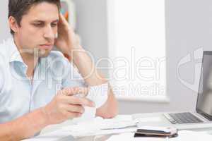 Worried man paying his bills online with laptop at home