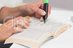 Hands highlighting text in book on the table