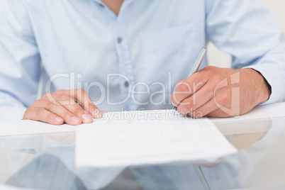 Close-up mid section of a man writing documents