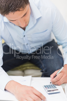 Close-up of a young man with bills and calculator