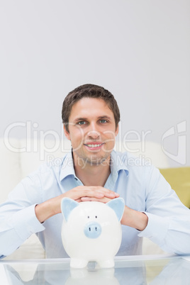 Handsome casual man with piggy bank in living room