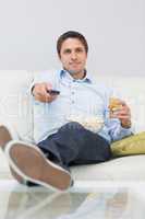 Man with a drink and remote control sitting on sofa