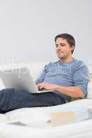 Relaxed young man using laptop in living room
