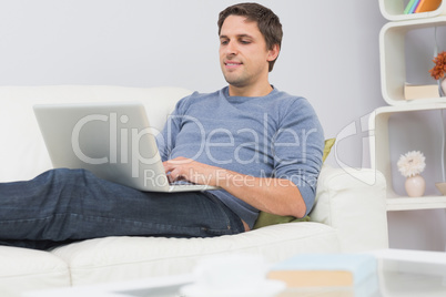 Relaxed young man using laptop in living room