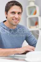 Smiling man using laptop in living room