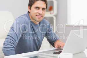 Portrait of smiling man using laptop in living room