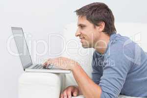 Smiling young man using laptop in living room