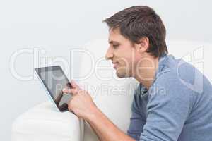 Smiling young man using digital tablet in living room